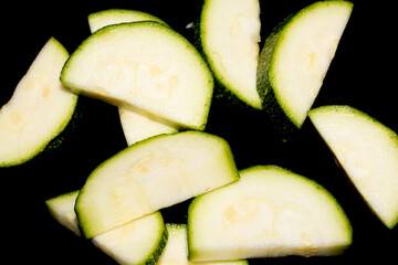 Close up of cut chopped home grown courgette zucchini on black background