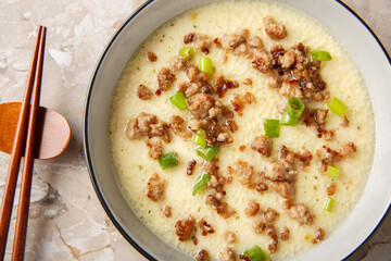 Chinese soft food steamed egg  crispy minced pork and green onion closeup in the bowl on the table. Horizontal top view from above