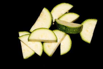 Close up of cut chopped home grown courgette zucchini on black background
