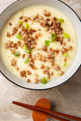 Asian Steamed Eggs with fried Pork mince and green onion closeup in the bowl on the table. Vertical top view from above