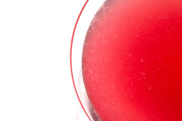 Close up abstract of a red cosmopolitan cocktail in a martini glass on white background