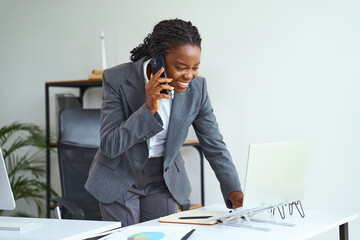 Professional Woman Engaged In Business Communication On Phone While Working On Laptop. Confident...
