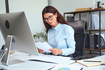 Focused Businesswoman Reviewing Documents In Modern Office, Engaged In Analytical Tasks; Concept Of...