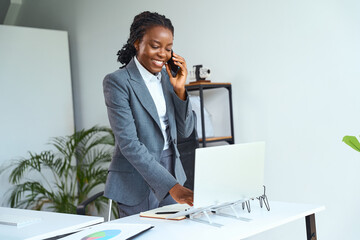 Professional Woman In Business Attire Talking On Phone Working At Desk, Modern Office Environment...