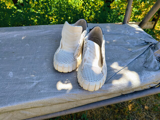 white sneakers. white shoes. Sneakers drying on window sill against green backdrop. Urban lifestyle...