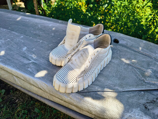 white sneakers. white shoes. Sneakers drying on window sill against green backdrop. Urban lifestyle...