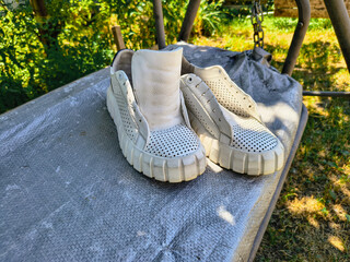 white sneakers. white shoes. Sneakers drying on window sill against green backdrop. Urban lifestyle...