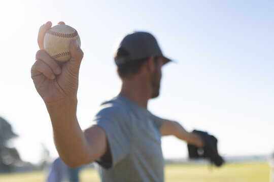 Man holding baseball wearing black glove while standing on baseball field in dark cap, copy space