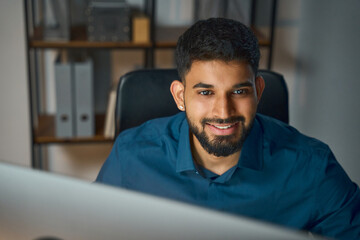 Man Smiling Confidently While Working On A Computer In A Modern Office Workspace, Demonstrating...
