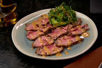 Deliciously Plated Sliced Meat with Tangy Sauce Served Alongside Fresh Greens Garnish on a Colorful Dish