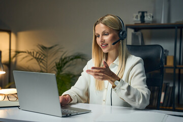 Professional Woman Wearing Headset Conducting Virtual Meeting On Laptop In Modern Office Workspace,...