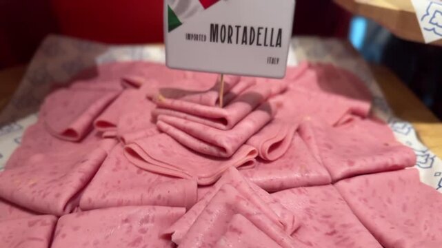 Detailed close-up of sliced mortadella ham highlighting pink texture and white fat spots in a fresh appetizing view.
