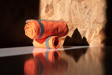 Close-up of rolled orange microfiber hiking towels. Bright outdoor gear for travel, hygiene, and post-shower relaxation. No people