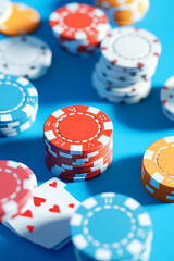 Colorful poker chips and playing cards arranged on a vibrant blue background, perfect for gaming themes
