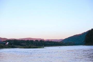 Fototapeta premium Serene landscape of a river winding gently through a valley with majestic mountains in the background soft hues of twilight