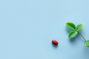 A light-blue surface with a red capsule and fresh leaves