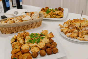 A savory assortment of appetizers including bread, mini pies, croquettes, and cheese dip is served...
