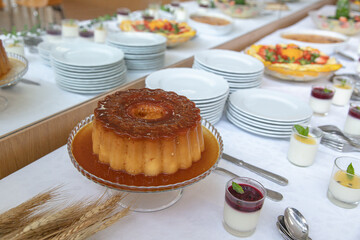 Homemade caramel pudding with golden sugar syrup as buffet centerpiece at a festive dessert table....