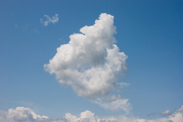 Bright blue sky, white fluffy clouds floating in the sky. This serene scene captures the beauty of...