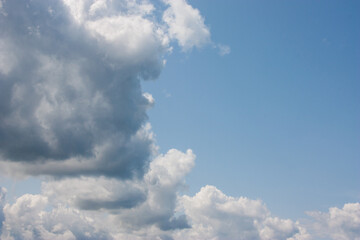 Bright blue sky, white fluffy clouds floating in the sky. This serene scene captures the beauty of...
