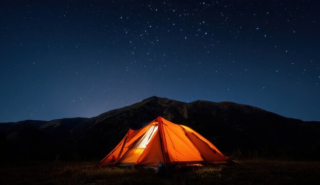 Illuminated tent glows warmly against a backdrop of majestic mountains and a starlit sky creating a serene and adventurous camping experience.