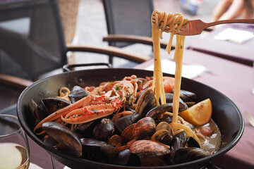 An image of spaghetti twirled on a spoon, served with a rich variety of fresh seafood.