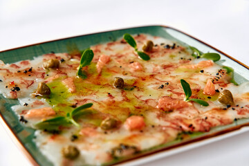 Delicately Arranged Carpaccio with Fresh Garnishes and Drizzled Olive Oil Served on a Textured...
