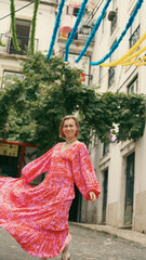 A tourist in a bright dress dances during a carnival on the streets of Lisbon. Soft focus