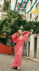 A tourist in a bright dress dances during a carnival on the streets of Lisbon. Soft focus