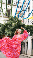 A tourist in a bright dress dances during a carnival on the streets of Lisbon. Soft focus