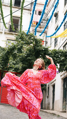A tourist in a bright dress dances during a carnival on the streets of Lisbon. Soft focus