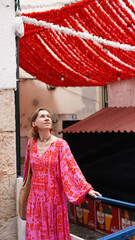 A tourist in a bright dress poses for a photo during carnival on the streets of Lisbon. Soft focus