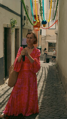 A woman in a bright dress broadcasts live from the streets of Lisbon during the celebration of San...