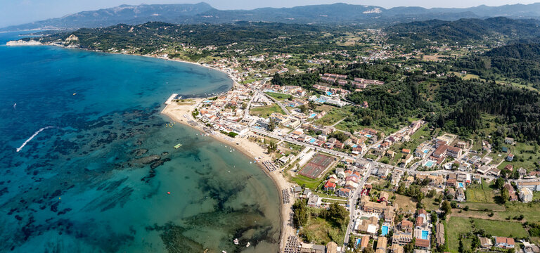 aerial landscape view of coastline in Sidari, located in northern part of Corfu Island with turquoise water, Paralia Sidari beach, Cityscape and wooded hilly landscape in background  