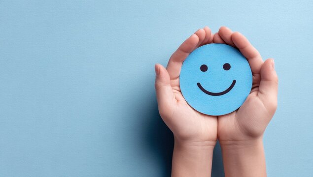 Hands gently cradle a light blue smiley face against a soft, calming blue background, symbolizing positivity and emotional well-being.