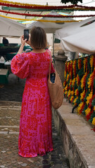 A woman in a bright dress takes pictures of the streets of Lisbon on her mobile phone. Carnival in...