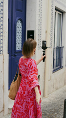 A woman in a bright dress broadcasts live from the streets of Lisbon during the celebration of San...