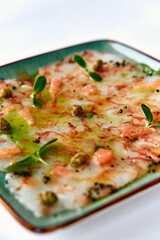 Delicate Seafood Carpaccio with Fresh Garnishes and Flavorful Drizzle, Offering a Colorful Presentation of Tantalizing Textures and Tasty Ingredients