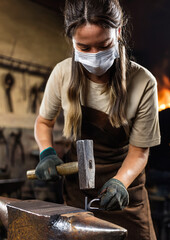 Fabbro donna mentre modella un pezzo di ferro