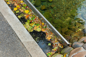 Metal mesh trap for trash and leaves in a stream. Modern infrastructure in a park or city garden