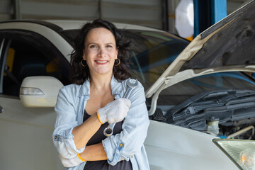 Small business garage mechanic woman inspects engine, focused on car repair with confidence and...
