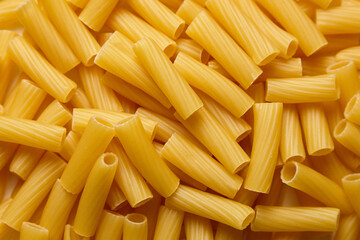 Close-up view of uncooked tortiglioni pasta pieces arranged in a scattered manner, showcasing their...