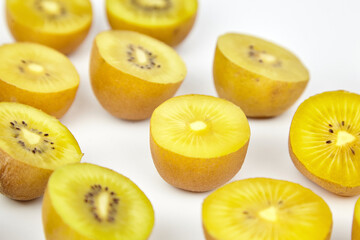Fresh yellow kiwifruit halves arranged artistically on a clean white background, showcasing vibrant...