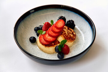 A Mouthwatering Dish Featuring Fluffy Pancakes Topped with Fresh Strawberries, Ripe Berries, and a Touch of Mint for a Colorful Culinary Delight