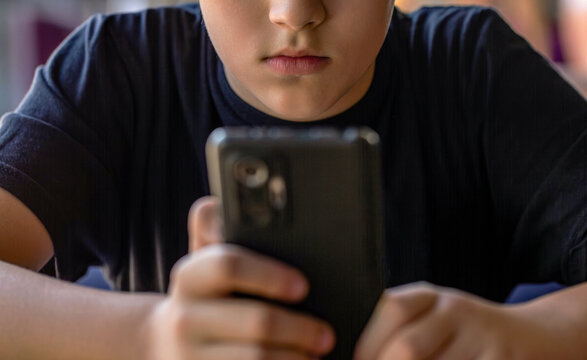 Boy with a serious face communicates on Internet. Child gadget addiction. Child, teenager or preteen mobile phone. Mobile addiction, digital dependence concept - Powered by Adobe