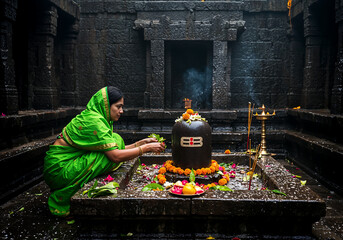 Woman in Green Saree Offering Bilva Leaves and Lotus on Shiva Lingam Amid Rain-Kissed Temple Steps
