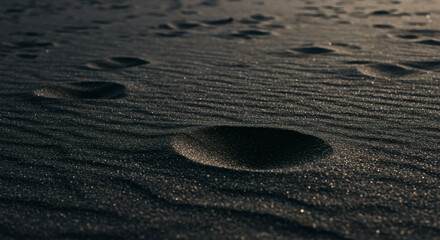 Close-up view of dark sand with footprints.