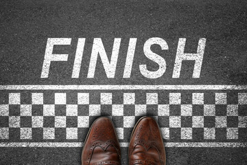 Businessman standing on asphalt concrete floor with finish line successful concept. Business goal's...