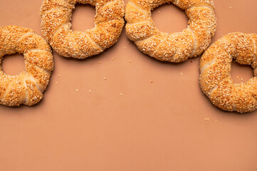 Simit or gevrek, round bagel with sesame seeds on brown background top view. Creative layout with food. Traditional Turkish pastry. Delicious fresh homemade pastry, bakery product. Bagel mockup