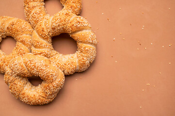 Simit or gevrek, round bagel with sesame seeds on brown background top view. Creative layout with food. Traditional Turkish pastry. Delicious fresh homemade pastry, bakery product. Bagel mockup